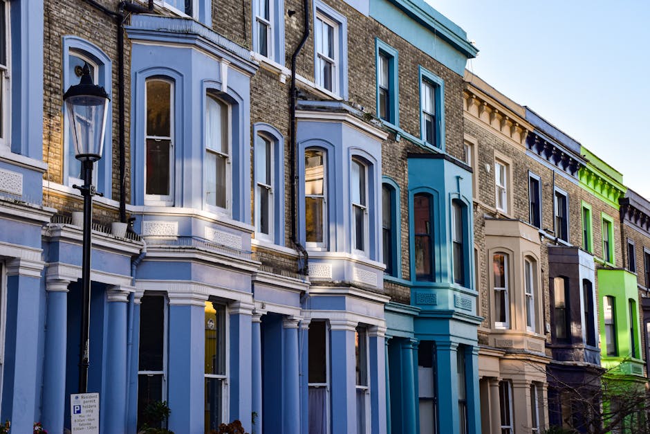 A row of elegant, white, multi-storey Victorian-style terraced houses with ornate architectural details, including decorative cornices, window pediments, and wrought iron balconies along the first-flo